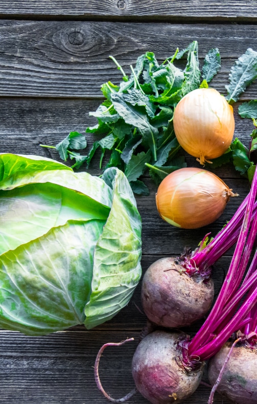 Rustic wooden table displaying a variety of fresh vegetables.