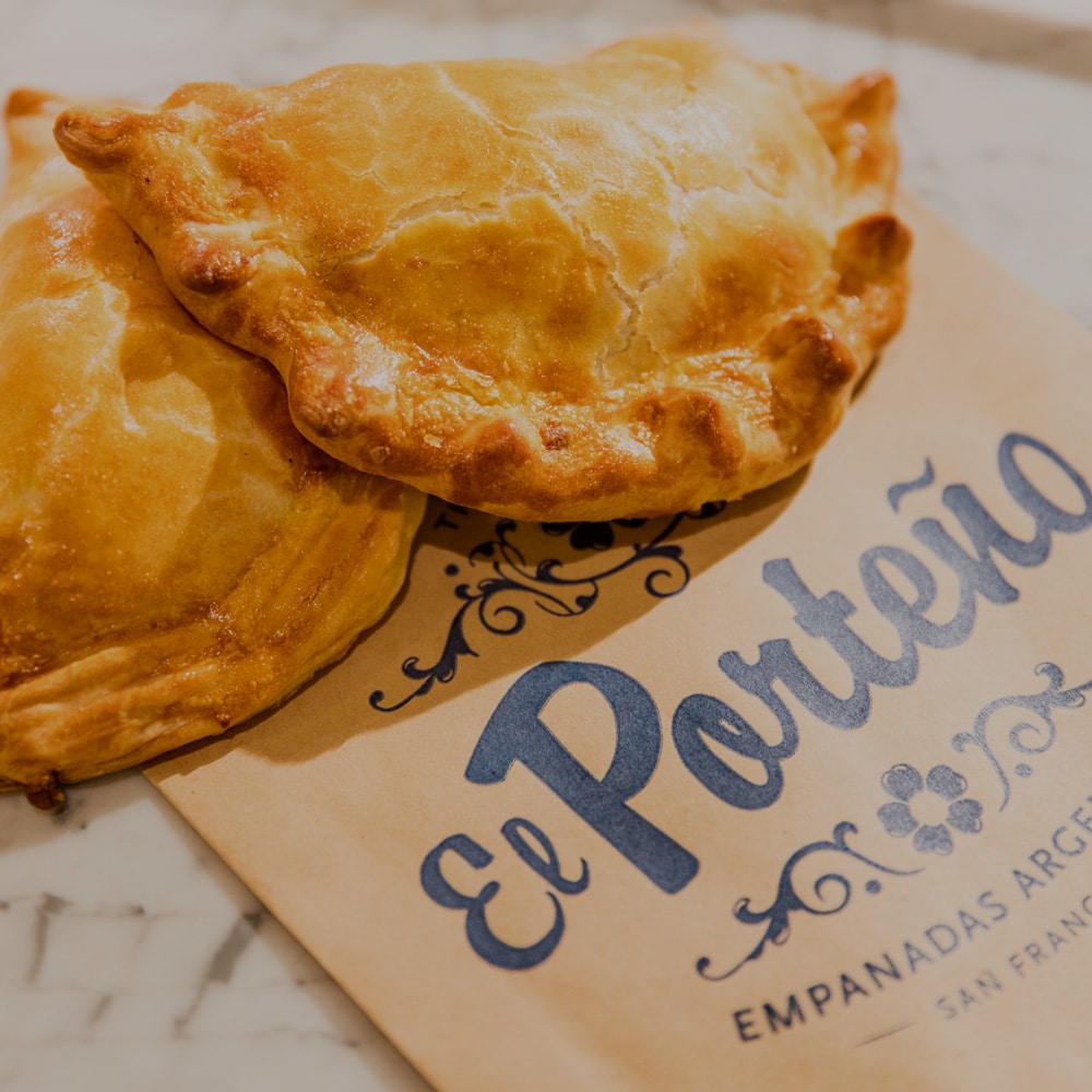 Two golden brown empanadas on a plate from El Porteño.